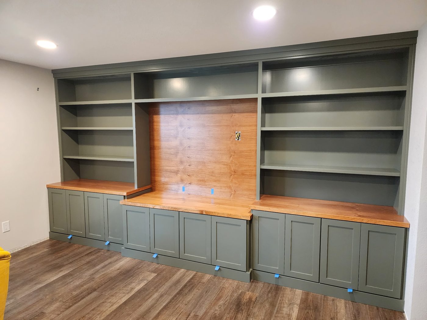 Custom built-in wall unit in sage green with a wood accent panel