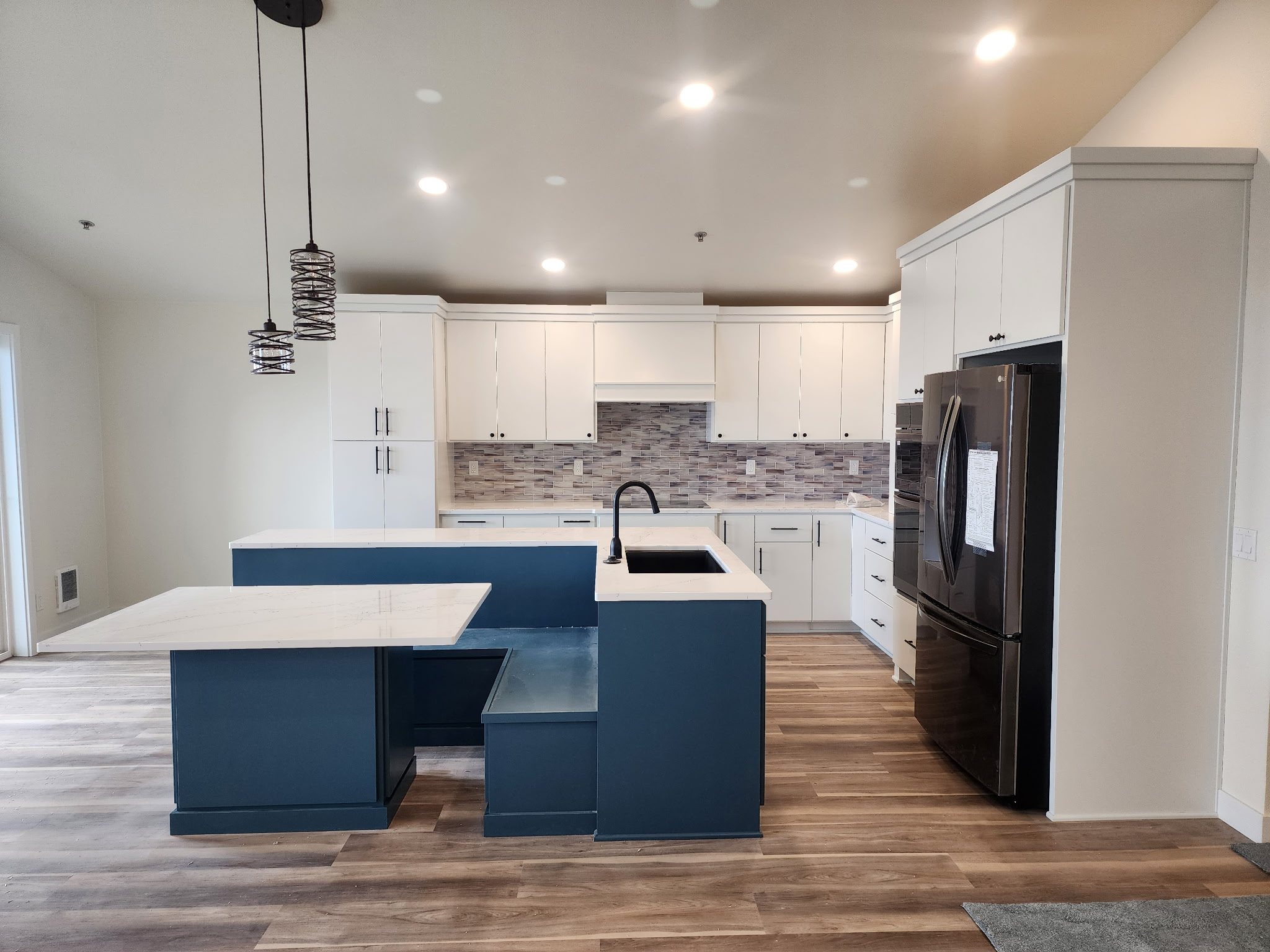 Open kitchen with navy blue island, built-in bench seating, and white perimeter cabinets
