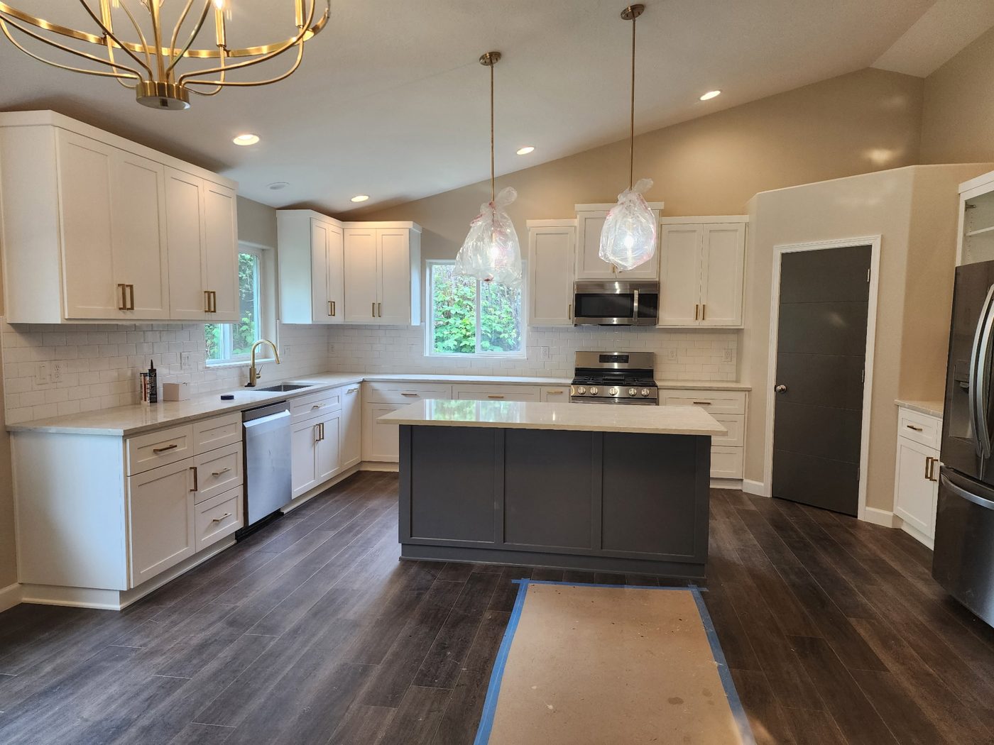 White and gray kitchen with gold hardware and a dark island